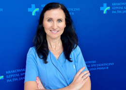 Dr n. med. Sylwia Wiśniowska-Śmiałek w medycznym ubraniu na granatowym tle