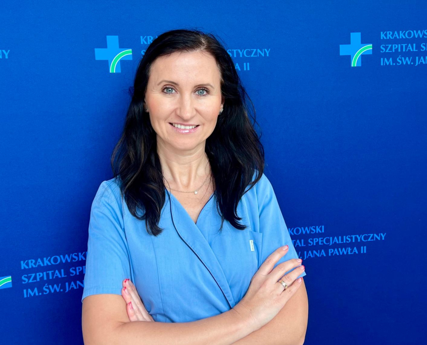Dr n. med. Sylwia Wiśniowska-Śmiałek w medycznym ubraniu na granatowym tle