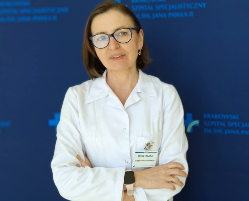 mgr Małgorzata Grudniewska w medycznym ubraniu na granatowym tle