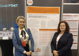 Dwie osoby na tle plakatu podczas konferencji.