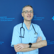 dr n. med. Michał Harańczyk w medycznym ubraniu na granatowym tle