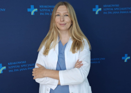 Dr Elżbieta Ostrowska-Kaim na tle ścianki ze szpitalnymi logotypami.