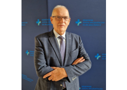 prof. Piotr Podolec na tle ścianki z logotypem Szpitala.