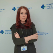 p. Zdechlik na tle ścianki z logotypem szpitala.