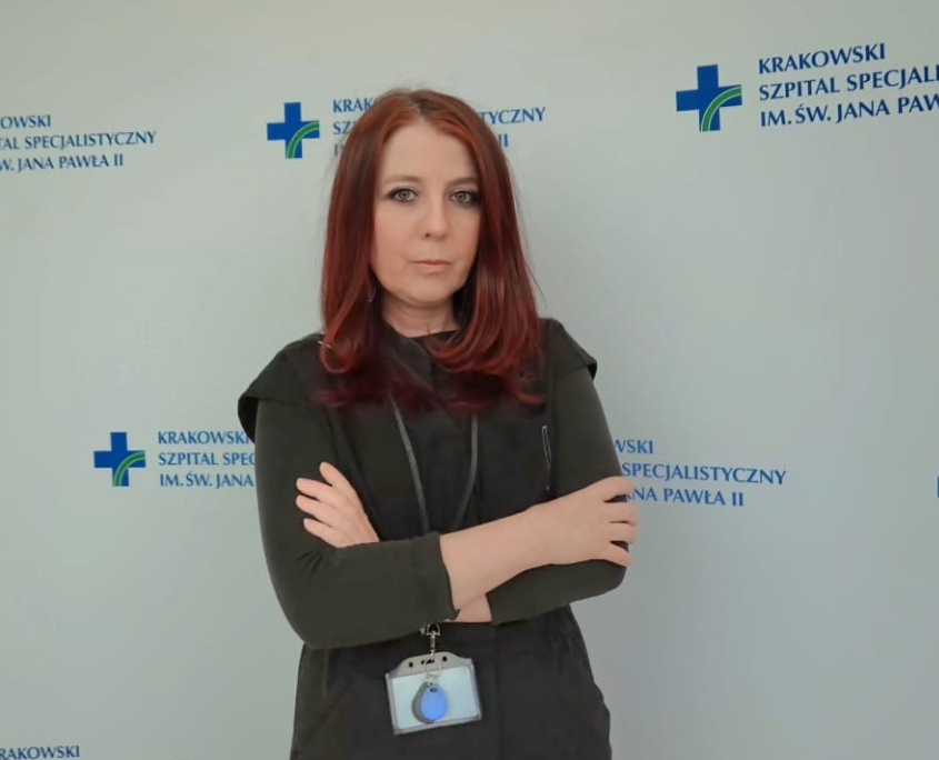 p. Zdechlik na tle ścianki z logotypem szpitala.