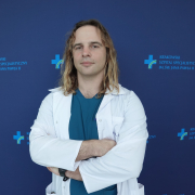 mgr Łukasz Marszałek w medycznym ubraniu na granatowym tle