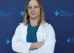 mgr Łukasz Marszałek w medycznym ubraniu na granatowym tle