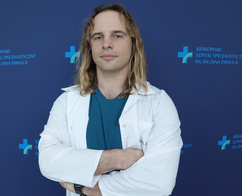 mgr Łukasz Marszałek w medycznym ubraniu na granatowym tle