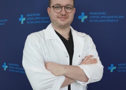 mgr Piotr Rutkowski w medycznym ubraniu na granatowym tle