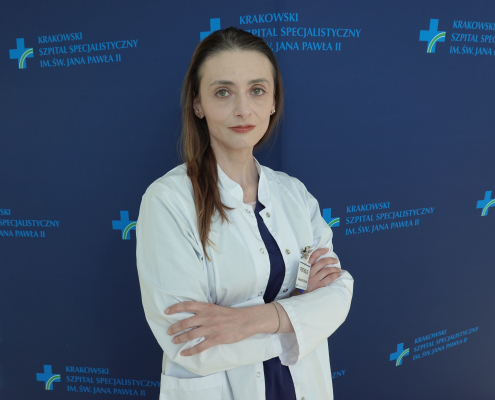 Psycholog na tle ścianki z logotypem szpitala.