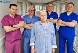 Zespół przeprowadzający zabieg - 4 lekarzy i pacjent na szpitalnym korytarzu.