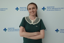 Dr Michno na tle ścianki z logotypem szpitala.