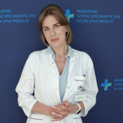 Dr hab. n. med. Magdalena Kopytek an tle granatowej ścianki z logotypem Szpitala.