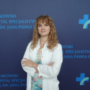 Katarzyna Tworzydło na tle granatowej ścianki z logotypem szpitala.