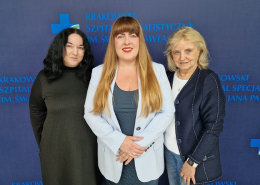 Prof. Komar, Dr Holcman i prof. Kostkiewicz na ściance w kolorze granatowym z logotypami Szpitala.