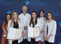 Kolorowe zdjęcie grupowe sześciu osób w strojach medycznych na granatowym tle z logotypem Szpitala.