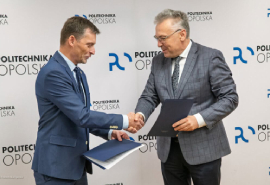 Prorektor ds. Ogólnych Politechniki Opolskiej wraz z Dyrektorem Szpitala lek. Grzegorzem Fitasem podczas podpisywania umowy o współpracy na tle ścianki z logotypami Politechniki Opolskiej.