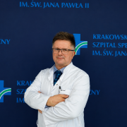 Dr Mirosław Nęcki na tle ścianki z logotypem szpitala.