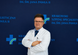 Dr Mirosław Nęcki na tle ścianki z logotypem szpitala.