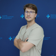 lek. Kamil Marzec w medycznym ubraniu na granatowym tle