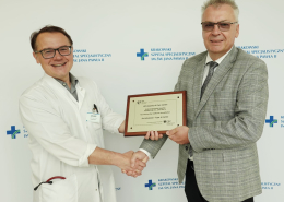 Profesor Paweł Rubiś i Dyrektor Szpitala Grzegorz Fitas na tle ścianki z logotypami Szpitala.