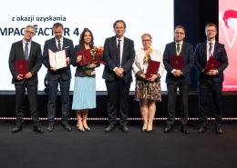 Siedem osób na grupowym zdjęciu podczas odbioru nagrody.